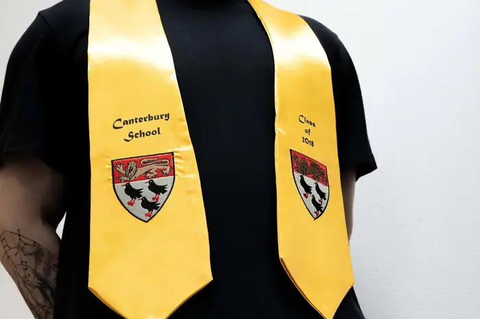 Beca de raso amarilla con escudos y textos bordados para un colegio