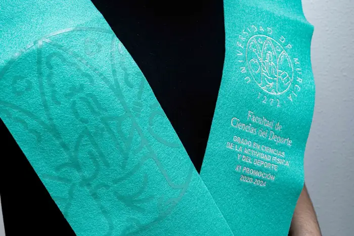 Beca de fieltro turquesa con escudo y textos serigrafiados en blanco