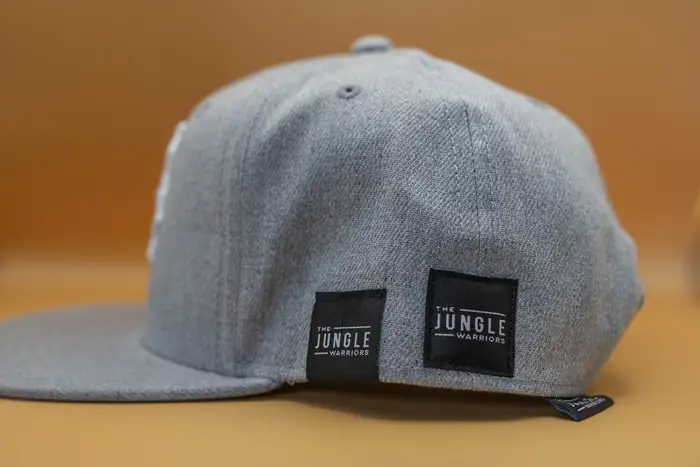 Gorra gris con dos etiquetas tejidas de marca en la parte trasera