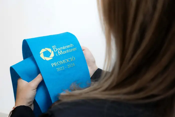 Beca azul de promoción sujeta a la espalda de una graduada