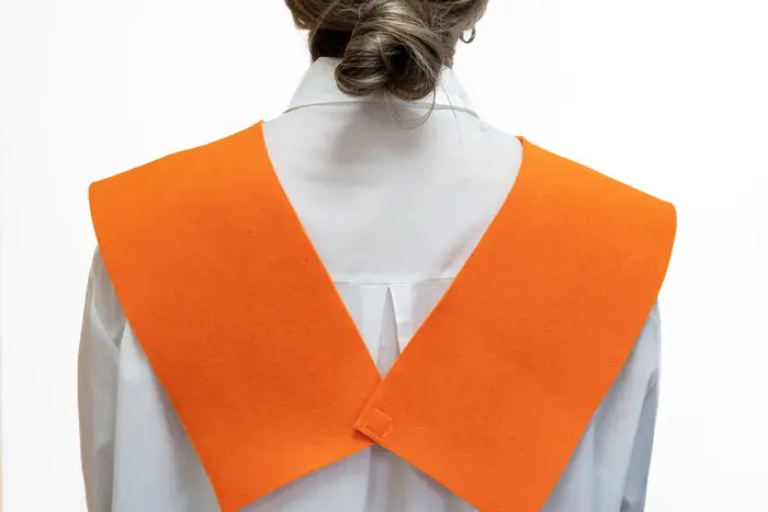 Terminación cruzada de una beca naranja sobre camisa blanca