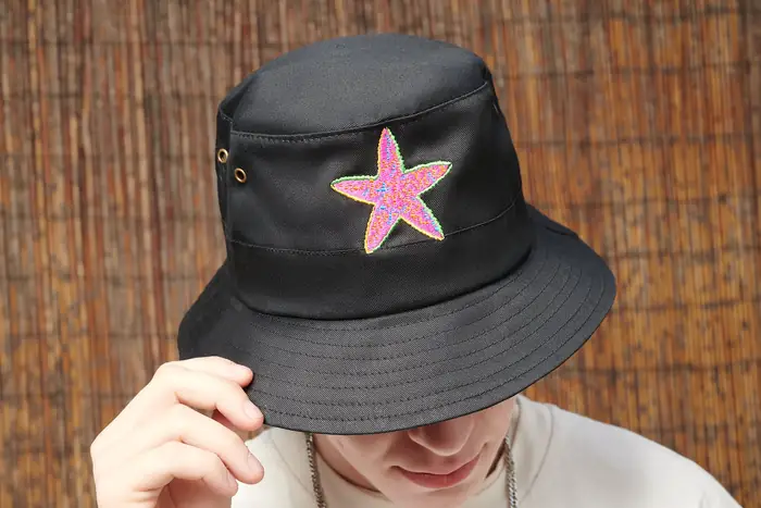 Gorro de pescador negro con estrella rosa bordada, puesto