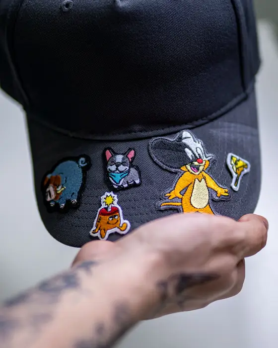 Mano colocando parches bordados sobre la visera de una gorra