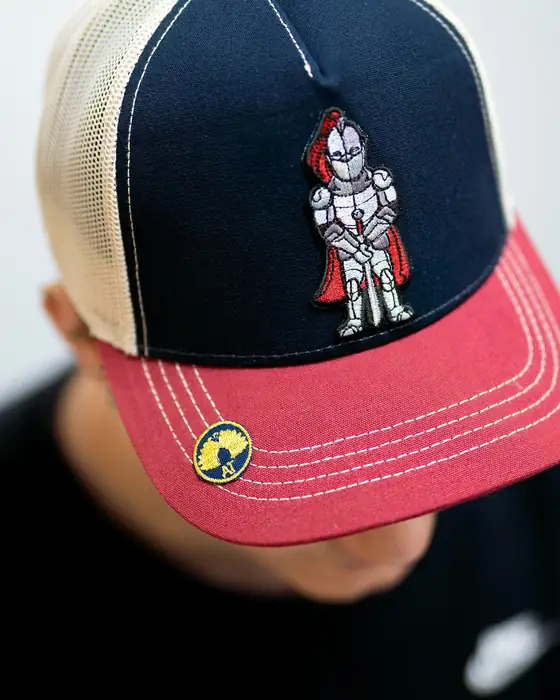 Gorra trucker roja y azul con parche bordado, puesta