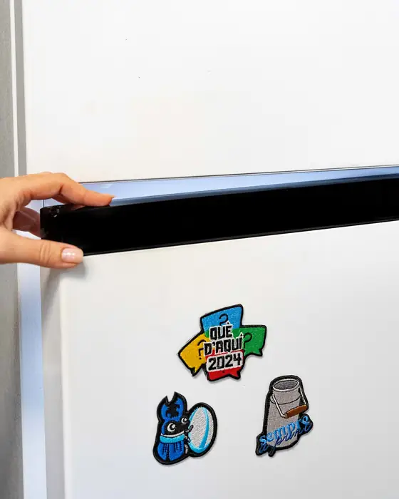 Mano colocando parches imantados en la puerta de una nevera