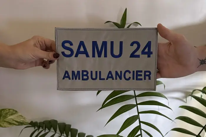 Manos sujetando un parche bordado SAMU para ropa de emergencias