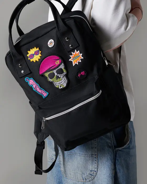 Mochila negra con parches bordados de colores, puesta