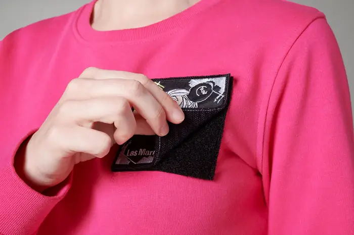 Mano colocando un parche de velcro en un jersey rosa
