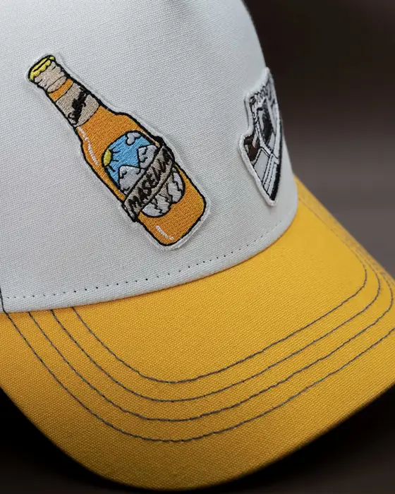 Gorra con visera amarilla y parches bordados cosidos en el frontal