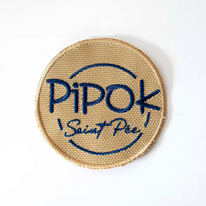 Parche bordado redondo Pipok sobre base de tejido beige