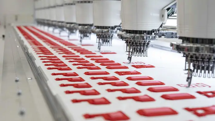 Máquina de bordar multicabezal trabajando un logo en el taller